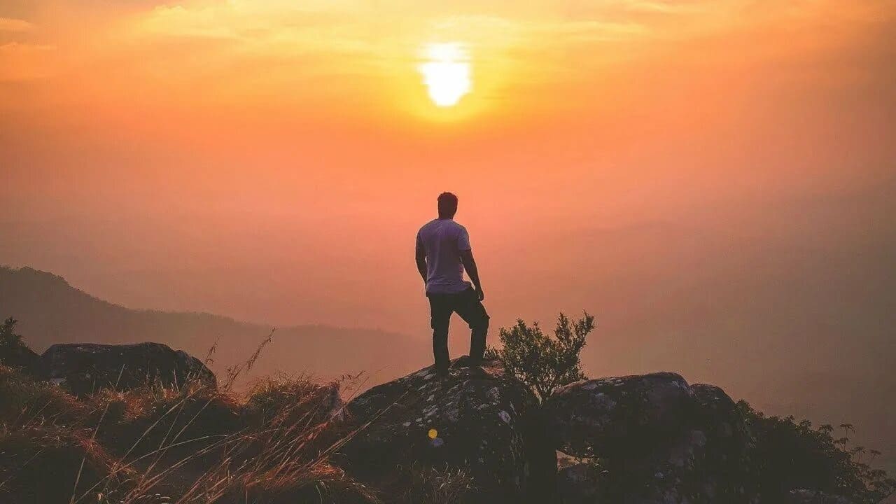 A person looking over a vast, beautiful landscape at sunrise.